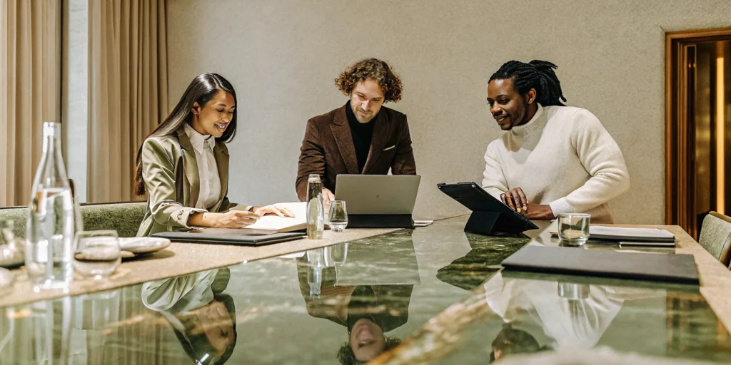 Business leaders reviewing branded merchandise and custom apparel spread across a conference table in a bright corporate boardroom