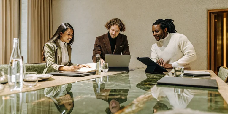 Business leaders reviewing branded merchandise and custom apparel spread across a conference table in a bright corporate boardroom